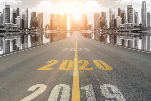 The number 2020 symbol represents the new year on the road heading to the city with beautiful skyscrapers background, New Year's and business target concepts.