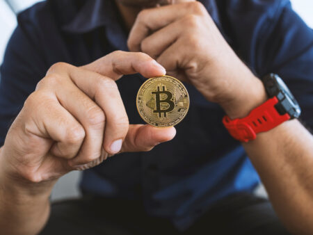 Mann hält Bitcoin in der Hand
