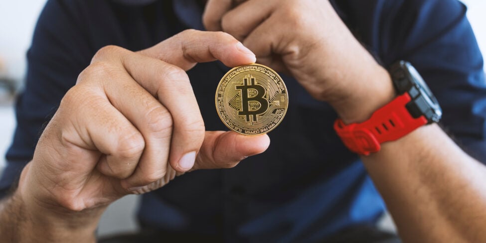 Mann hält Bitcoin in der Hand